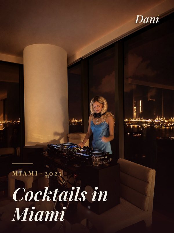 Cocktails in Miami, 2025: a DJ in a blue dress at the decks, floor-to-ceiling windows over the bay at night