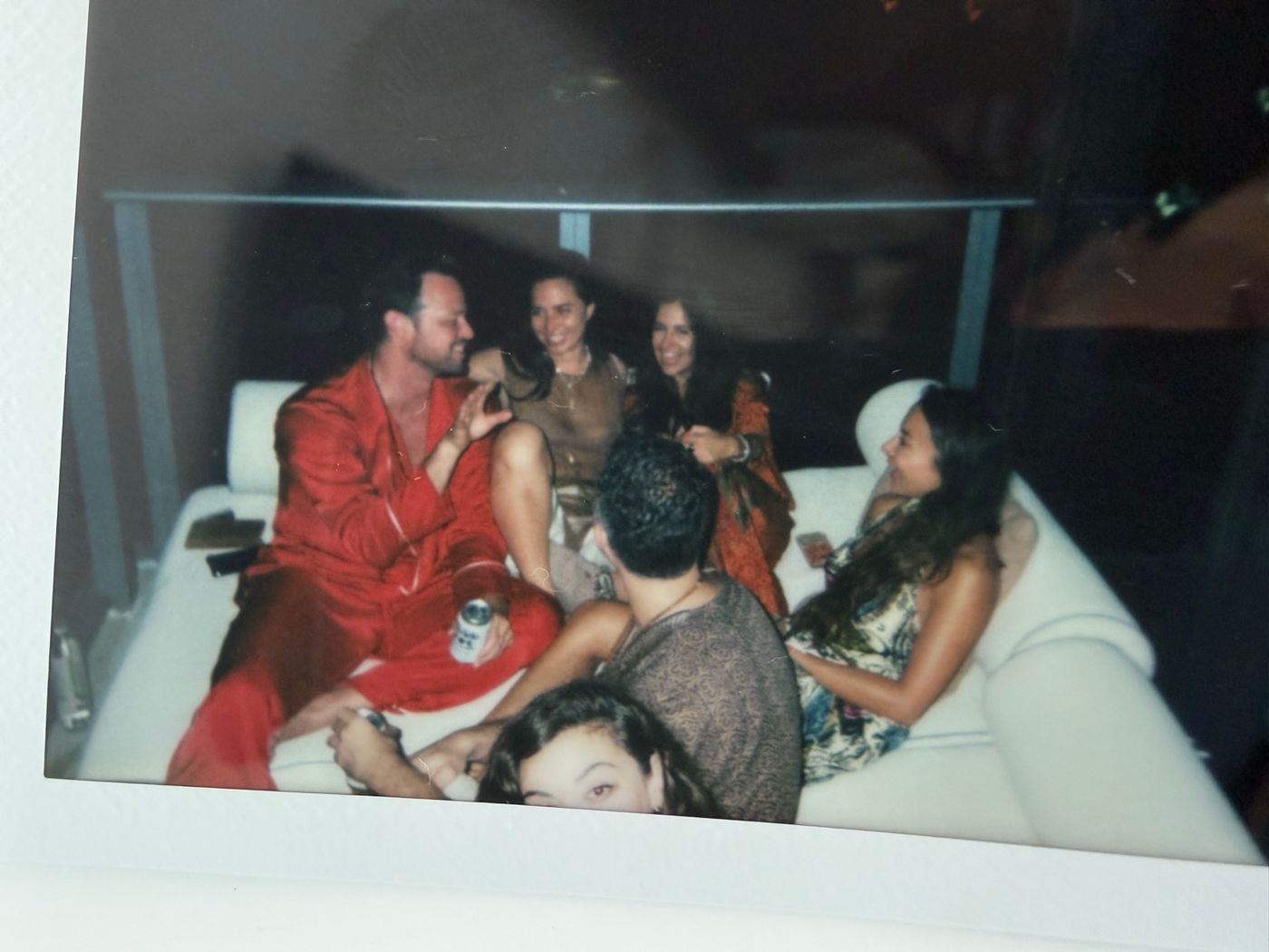 Polaroid of a group in silk robes on a white sofa